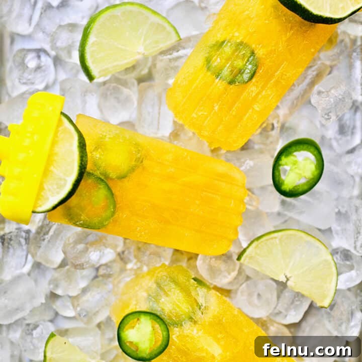 Delicious tropical margarita popsicles with jalapeno pepper slices over ice, garnished with lime.