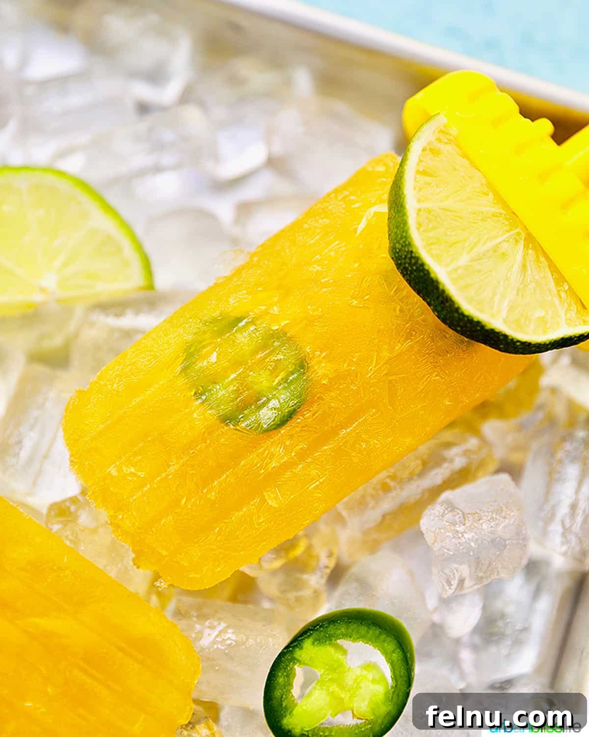 Island Oasis Margarita Pops 3 Close-up of a single vibrant yellow margarita popsicle, garnished with a green jalapeno slice, melting slightly on a bed of ice.