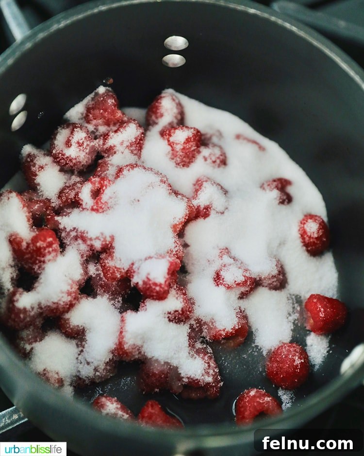 Making raspberry jam: raspberries and sugar in saucepan