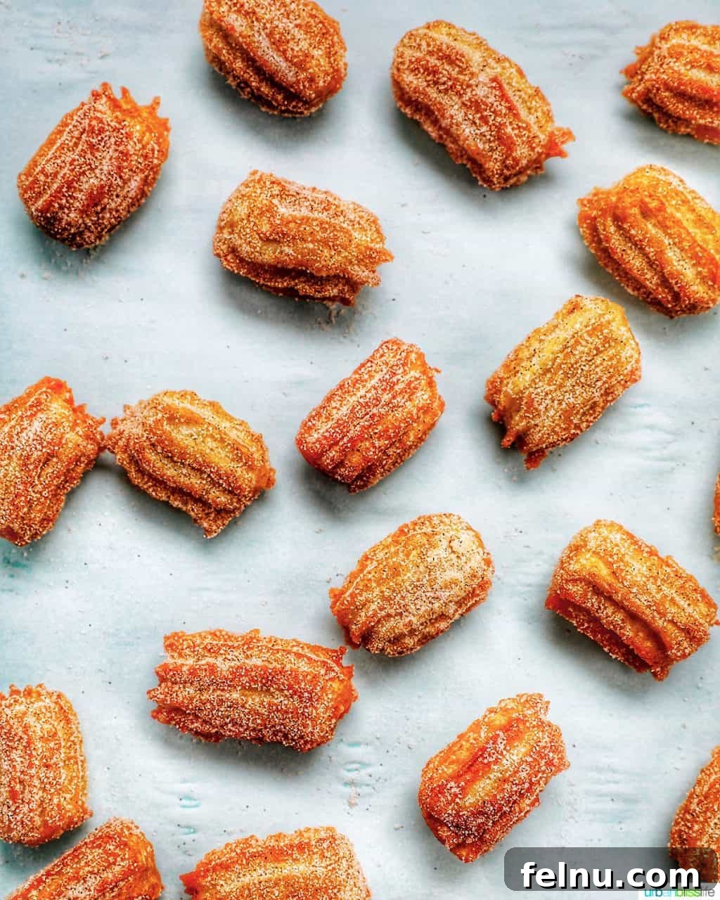 Homemade churro bites sprinkled on a baking sheet, ready to be enjoyed.