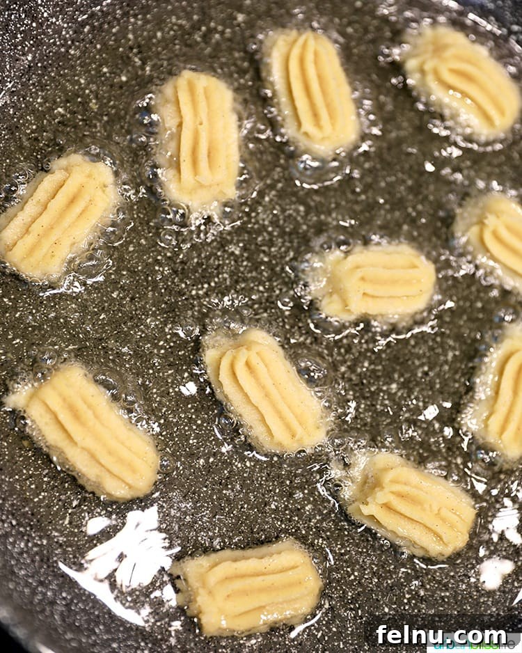 Piping churro dough directly into hot oil for frying.