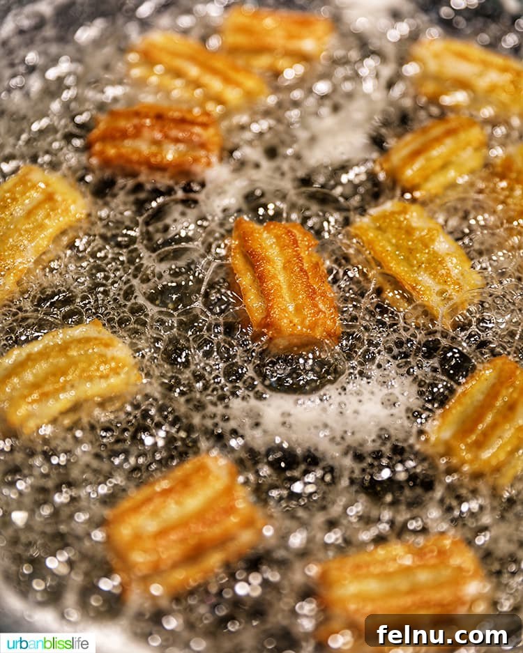 Churros frying in hot oil until golden brown and crispy.