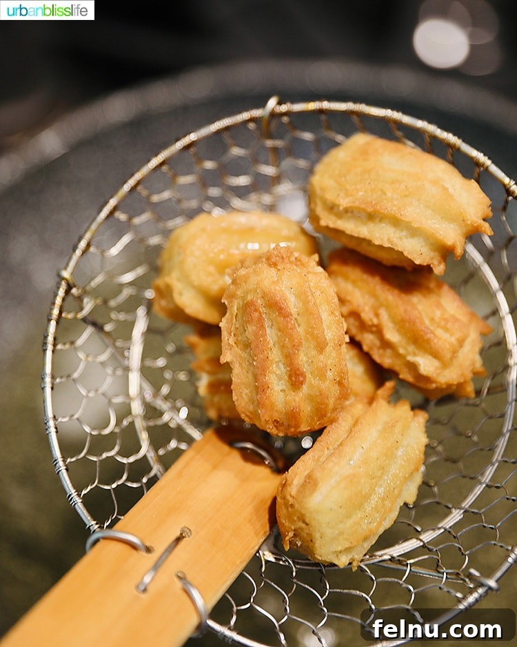 Using a spider strainer to remove cooked churros from the oil.