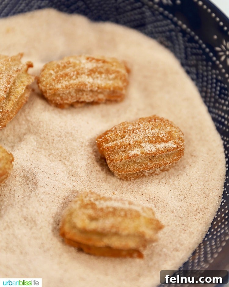 Coating the warm churros in a generous layer of cinnamon sugar.