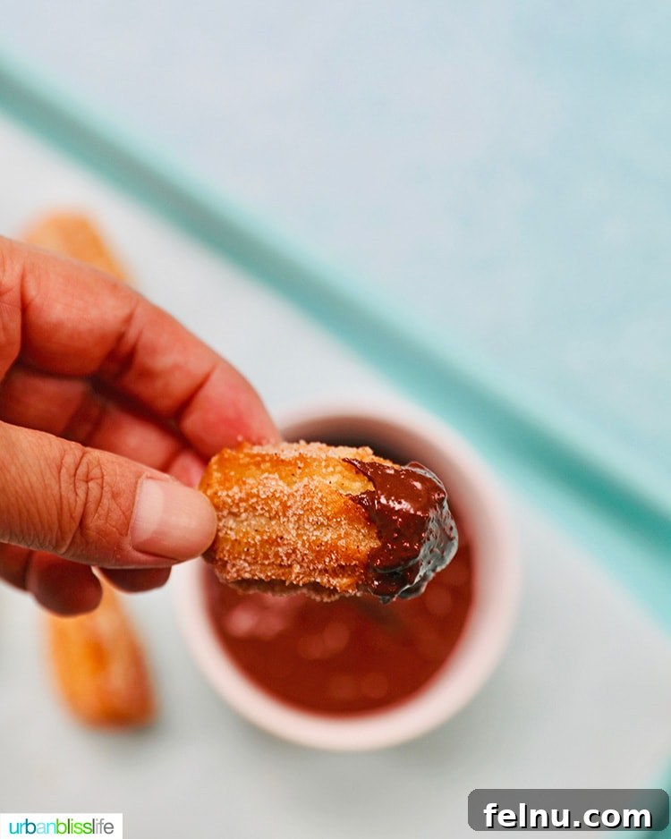 Dipping a crispy churro bite into a decadent chocolate sauce.