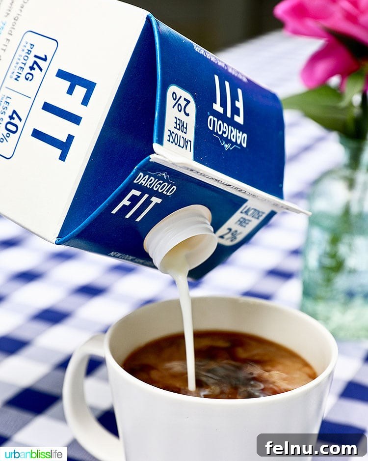 Elevate Your Everyday with Ultra-Filtered Milk 4 A hand pouring ultra-filtered milk into a steaming cup of coffee, creating a swirling blend of dark and light.
