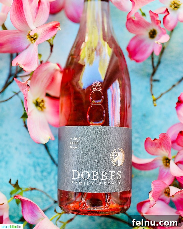 Toast to Summer: 12 Perfect Rosés for National Rosé Day 6 A bottle of Dobbes Rosé elegantly positioned next to a bouquet of fresh flowers, evoking a sense of summer charm.