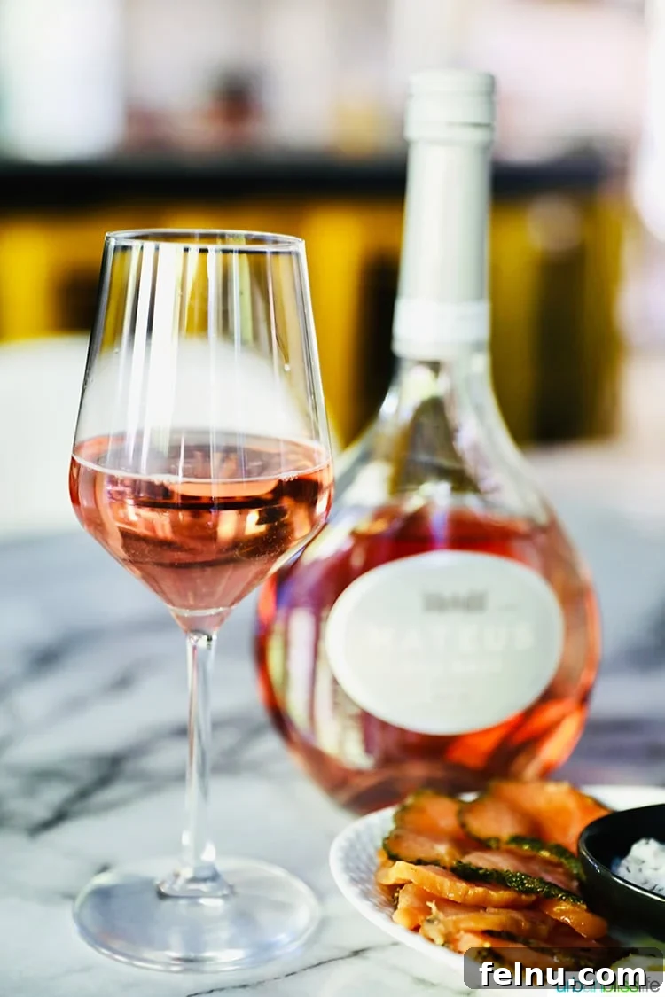 Toast to Summer: 12 Perfect Rosés for National Rosé Day 9 A glass of Mateus Rosé, with its distinctive bottle standing prominently in the background, iconic and inviting.