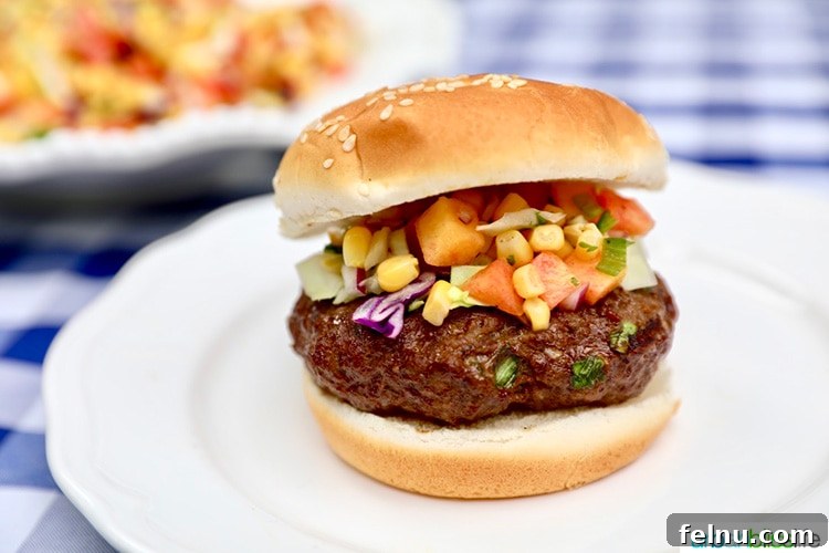 Close-up of an Asian beef burger with a bun, accompanied by a side of corn and cabbage slaw.