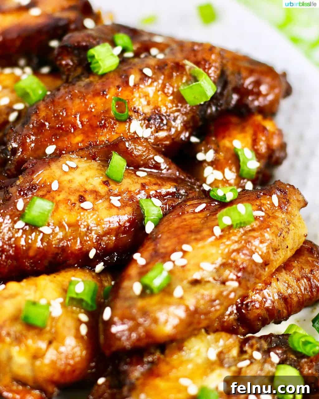 Glazed Teriyaki Chicken Wings 2 Delicious baked teriyaki chicken wings arranged on a serving platter, garnished with sesame seeds and chopped green onions, ready to be enjoyed.