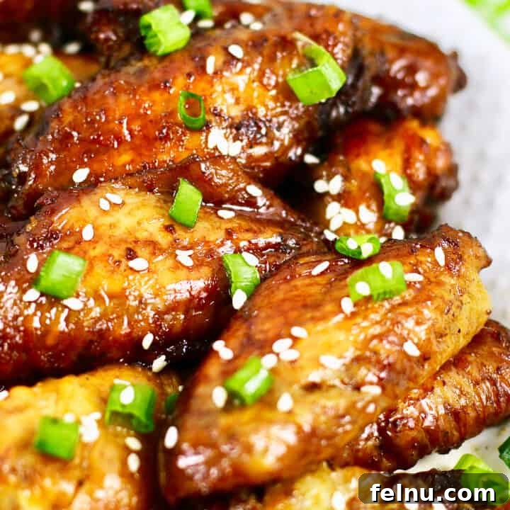 Perfectly baked teriyaki chicken wings with fresh green onions scattered on top, ready to serve.
