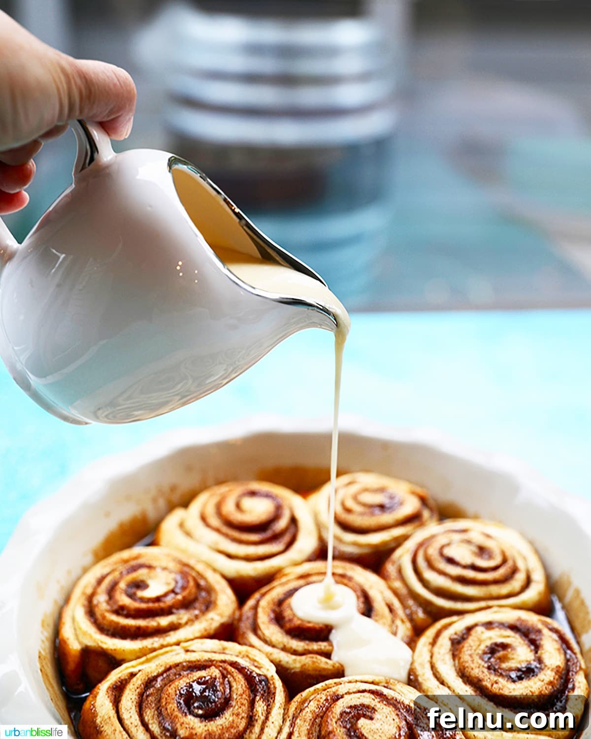Overnight Orange Spice Rolls 12 A luscious stream of icing being poured over a pan of warm, freshly baked orange cinnamon rolls.