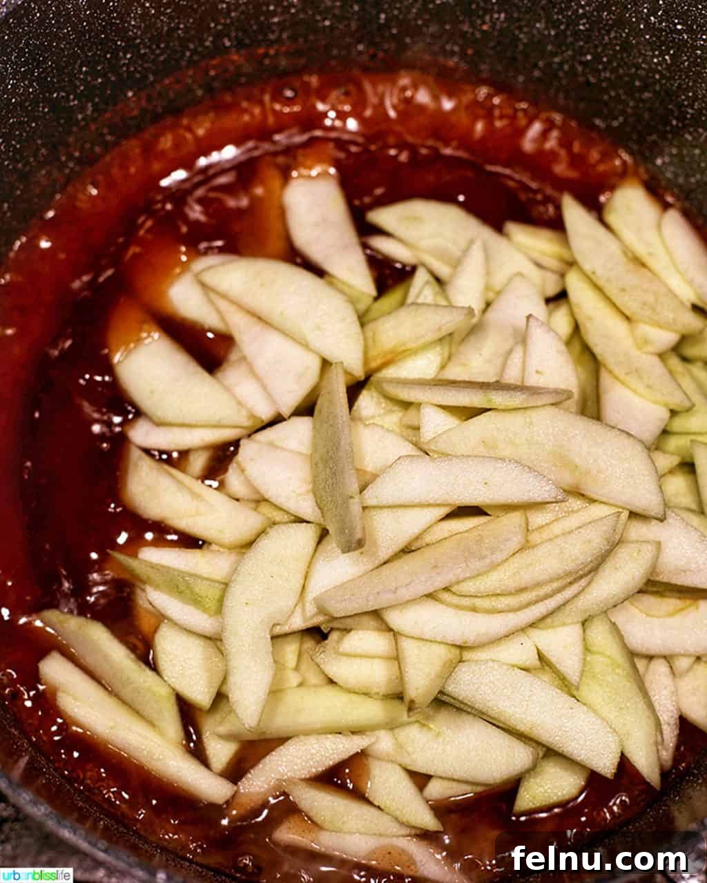 Homemade Freezer Apple Pie Filling 10 Apple slices being added to the bubbling spice mixture in a Dutch Oven