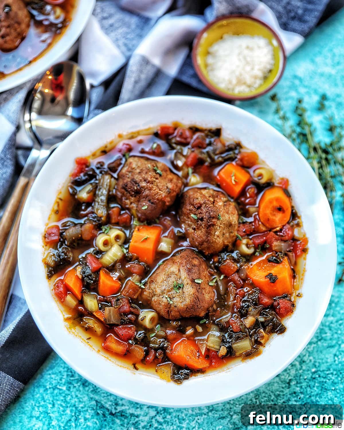 Hearty Slow Cooker Meatball Soup 2 Large white bowl of hearty meatball soup, garnished with fresh herbs and a side of Parmesan cheese, ready to be served.