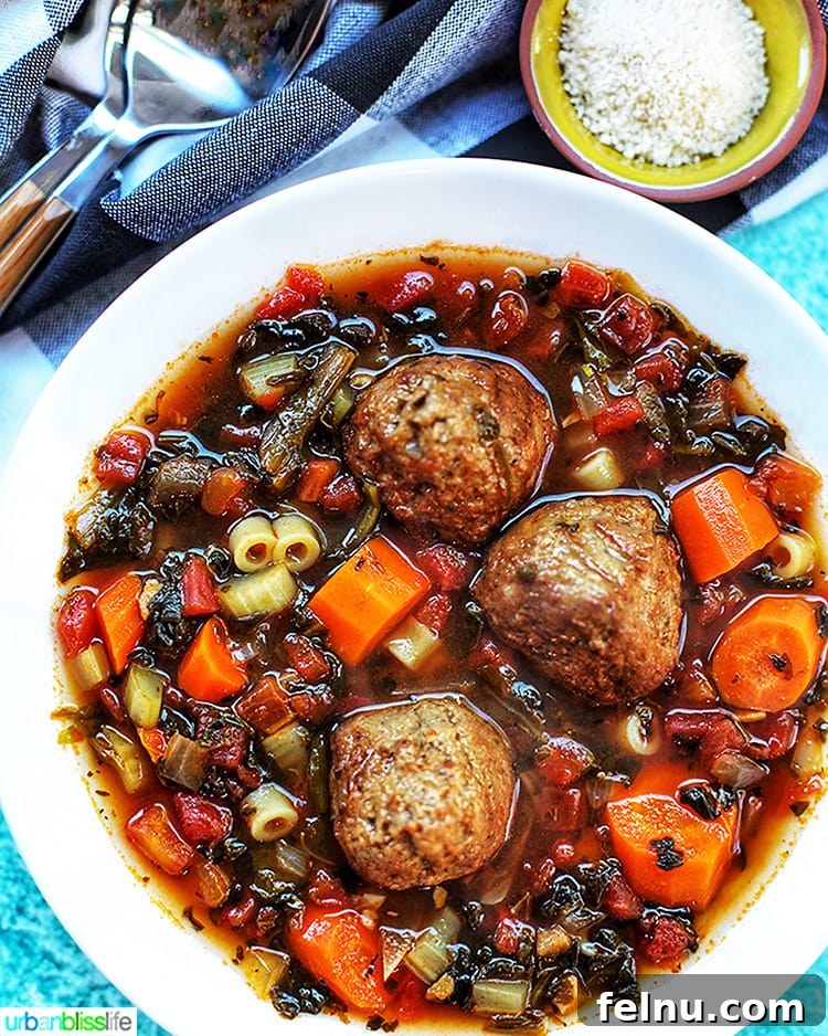 Hearty Slow Cooker Meatball Soup 4 A beautifully presented bowl of slow cooker meatball soup, rich with vegetables and pasta, beside a small bowl of grated Parmesan cheese.