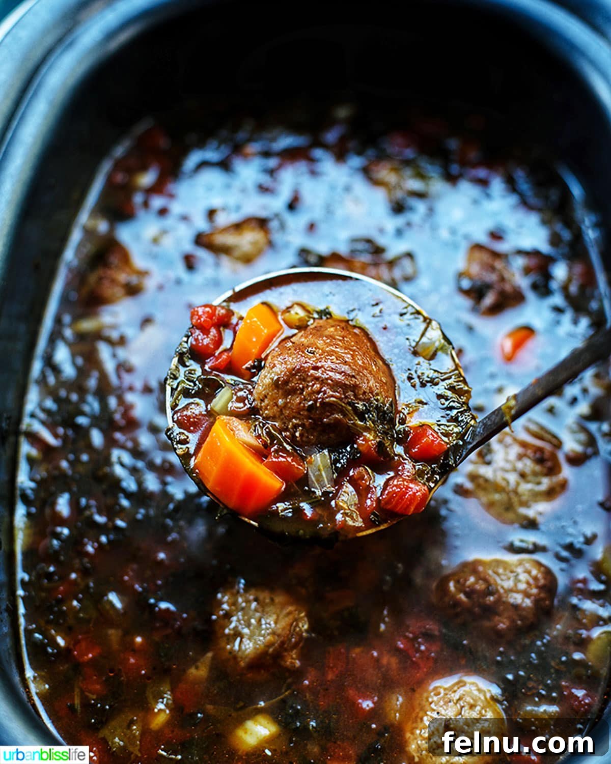 Hearty Slow Cooker Meatball Soup 6 A large spoon lifting a spoonful of meatball soup from a slow cooker, showing the rich broth and ingredients.