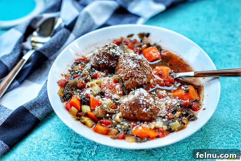 Hearty Slow Cooker Meatball Soup 7 Horizontal shot of a bowl of slow cooker meatball soup, generously topped with freshly grated Parmesan cheese and fresh herbs.