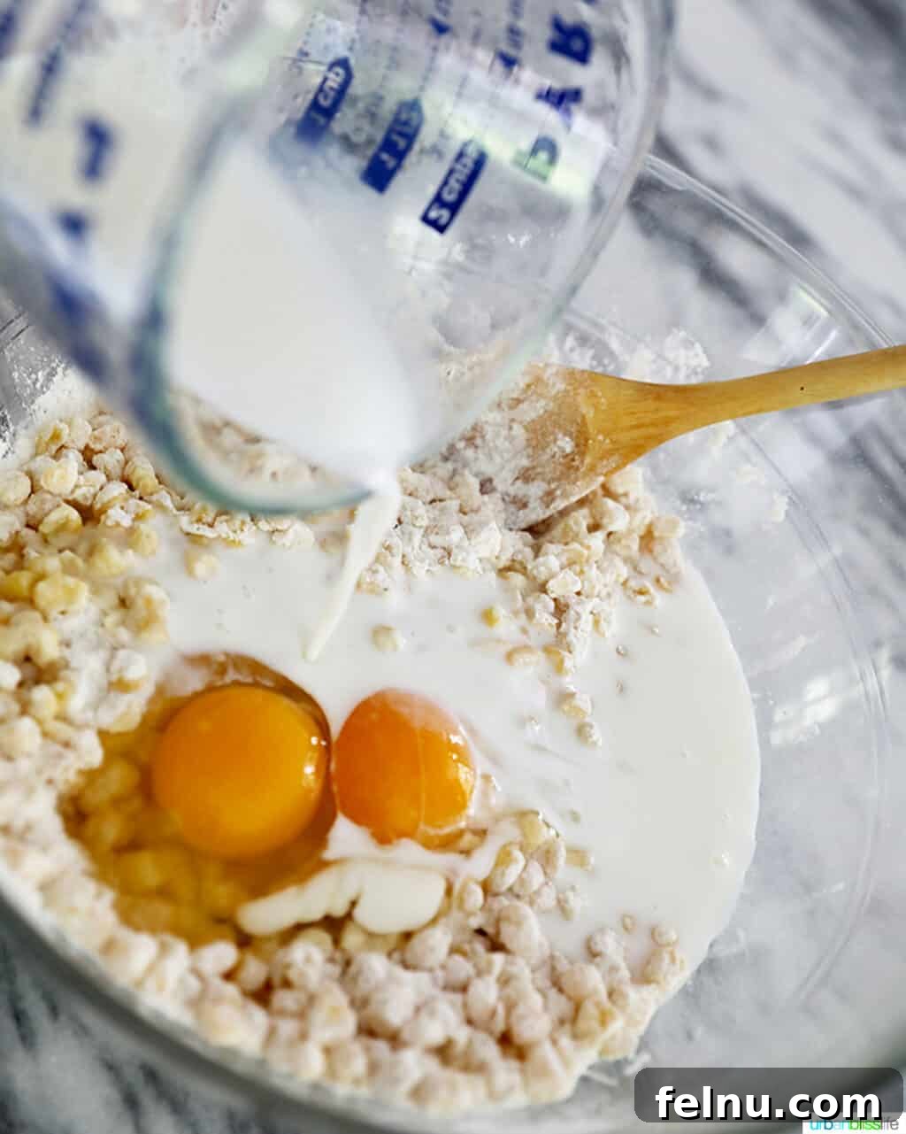 Golden Corn Fritters 5 Pouring milk into the corn fritter batter to achieve the perfect creamy consistency.