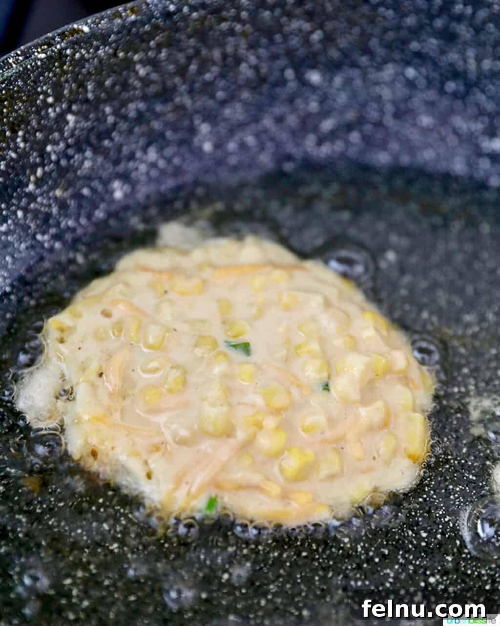 Golden Corn Fritters 9 A single corn fritter frying in a pan, achieving a golden hue.
