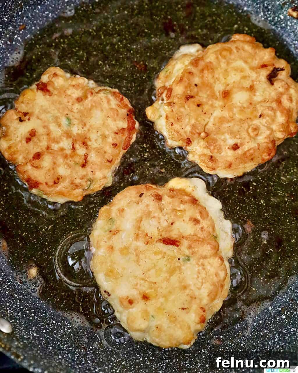 Golden Corn Fritters 10 Multiple corn fritters sizzling in a frying pan, cooking to crispy perfection.