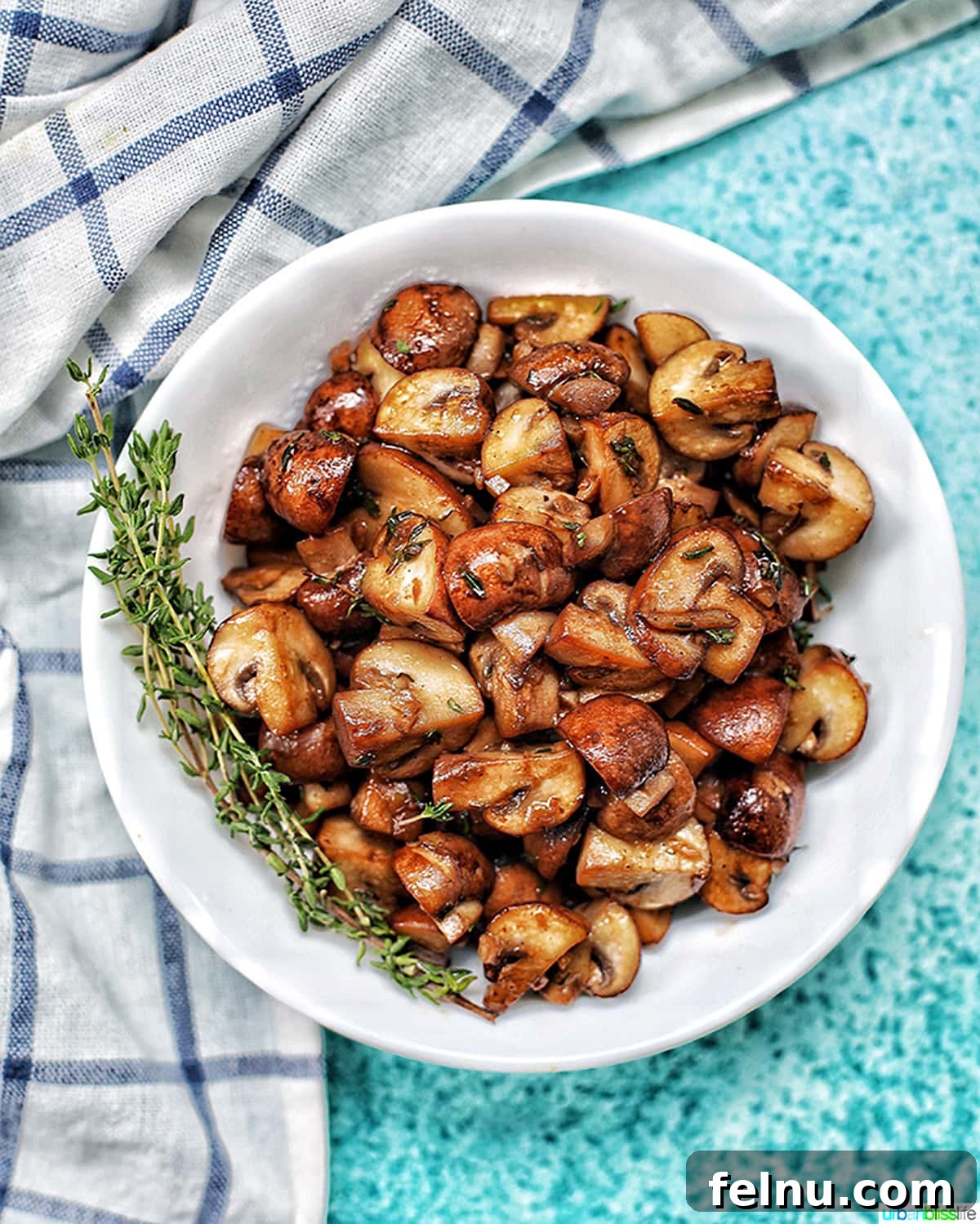 Savory Marsala Mushrooms 3 A vibrant bowl of mushroom marsala resting on a blue background, accompanied by a kitchen towel, ready to serve