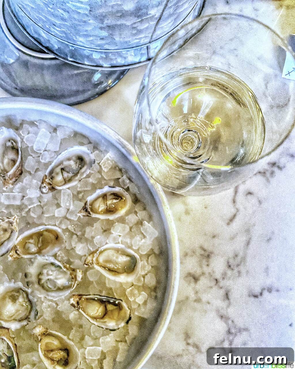 Portland's Top Romantic Dinner Spots 32 Glass of white wine beside a round tray of fresh oysters on ice at Normandie restaurant in Portland, Oregon.