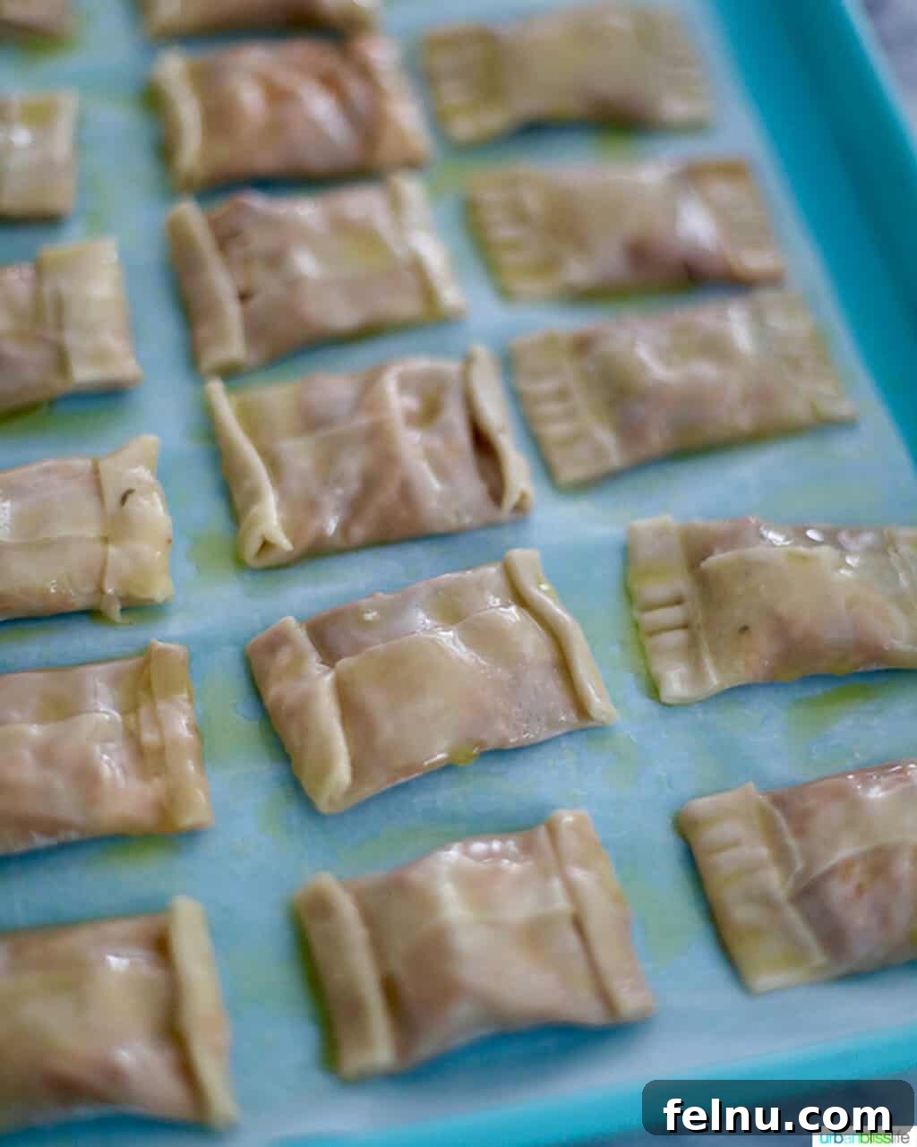 Crispy Air Fryer Pizza Rolls 14 prepped air fryer pizza rolls on blue baking sheet