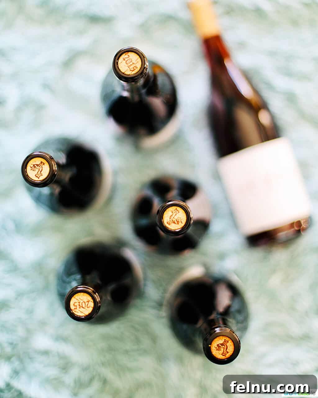 Top Oregon Pinot Noir Picks for Your Next Dinner Party 3 Oregon Pinot Noir bottles and corks arranged on a soft blue blanket