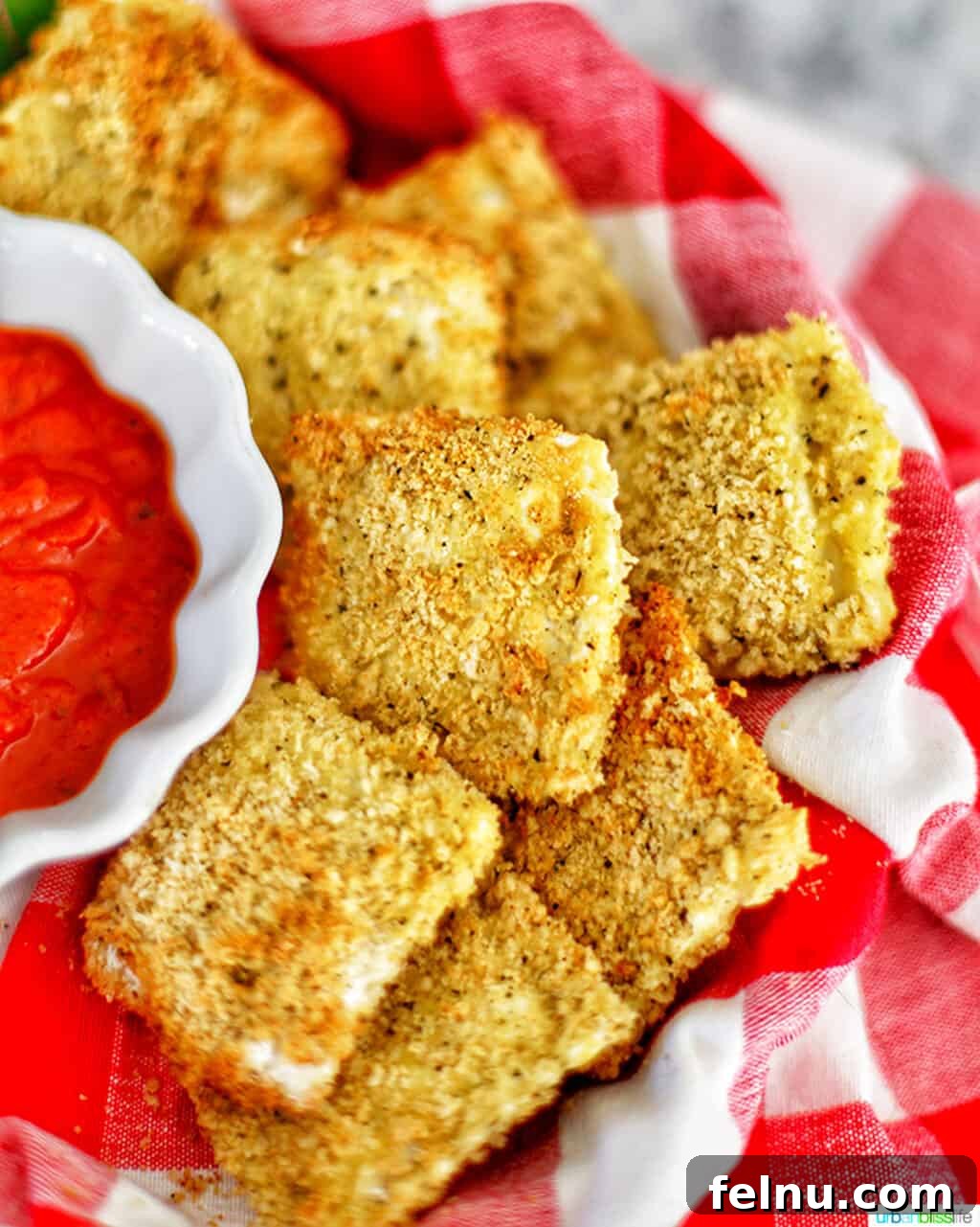 Air Fryer Ravioli Bites 2 Golden-brown Air Fryer Ravioli served with a flavorful dipping sauce.