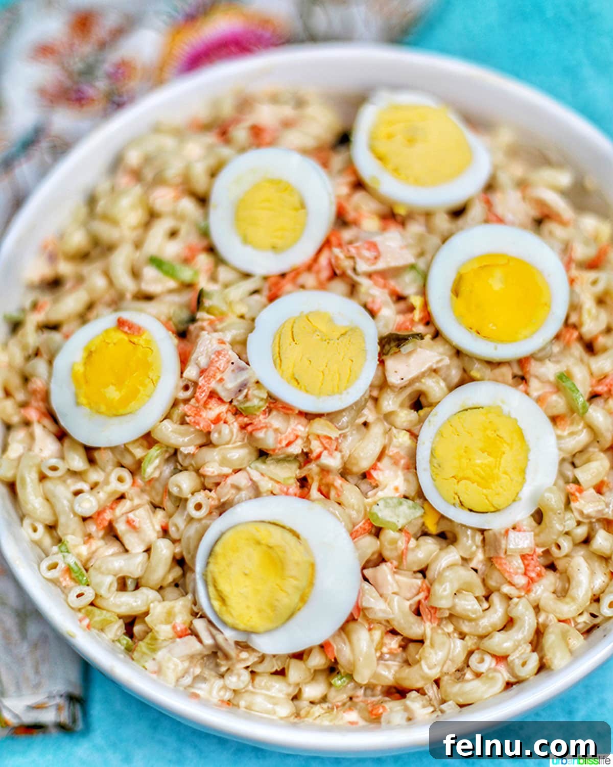 Filipino-Style Macaroni Salad 12 Filipino Macaroni Salad - macaroni, carrots, chicken, celery, pineapple, sliced hard-boiled egg- in a bowl.