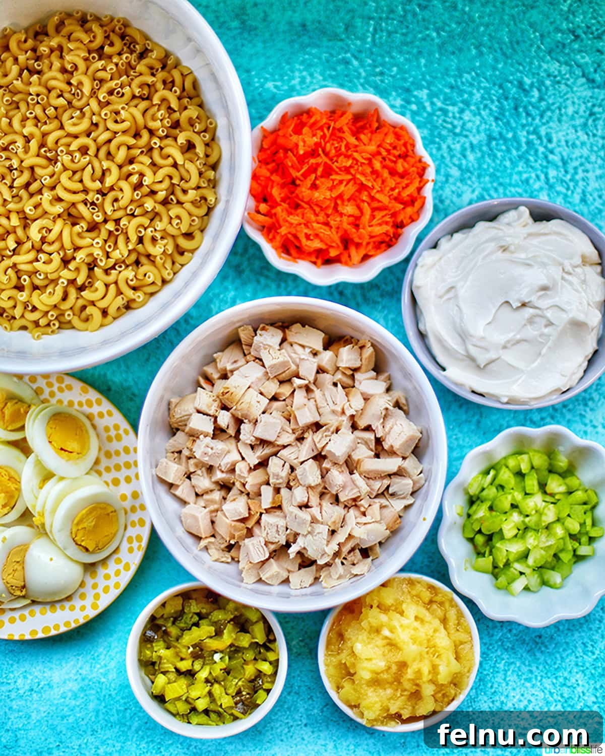 Filipino-Style Macaroni Salad 4 bowls full of ingredients to make Filipino Macaroni Salad on a bright blue background.