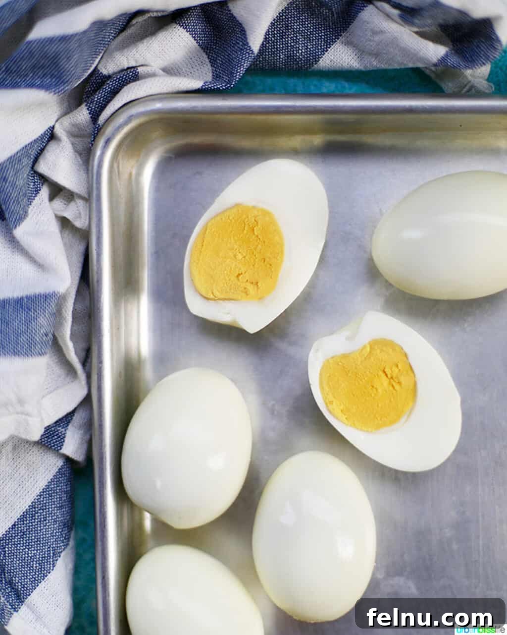 Perfect Hard Boiled Eggs with Ninja Foodi 3 Hard boiled egg cut open on a baking sheet, showcasing a perfect yellow yolk