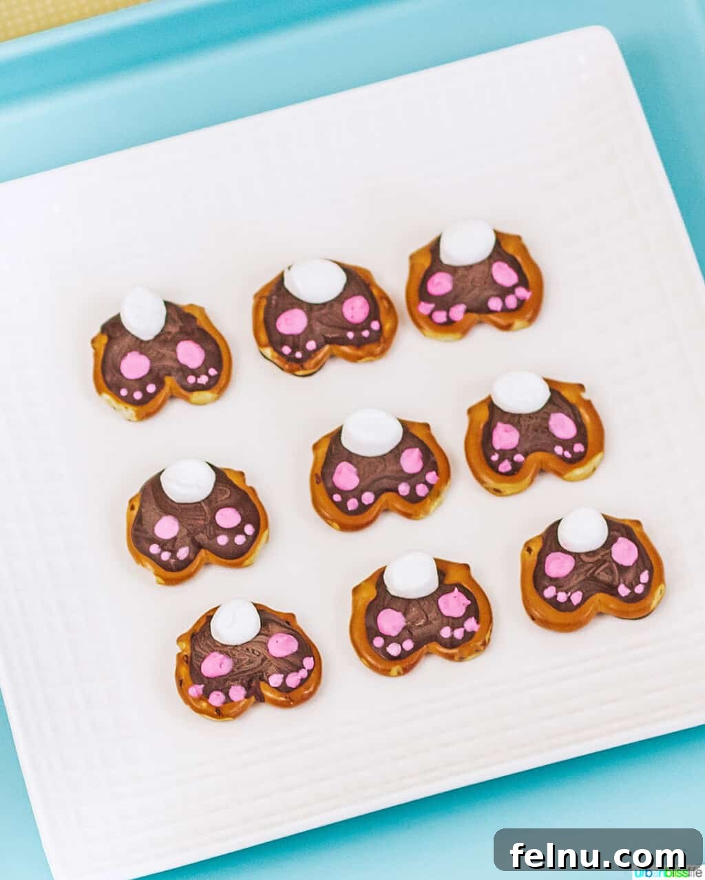 Whip Up Adorable Easter Bunny Pretzels 3 A full tray of freshly made Easter Bunny Pretzels, each with a chocolate-filled center, a fluffy white marshmallow tail, and tiny pink icing paws.