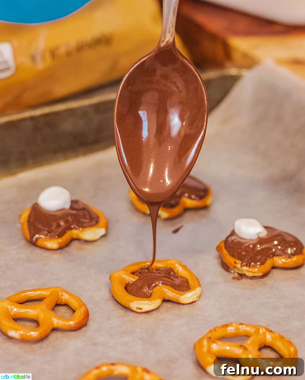 Whip Up Adorable Easter Bunny Pretzels 5 Melted chocolate candy coating being spooned into a pretzel, demonstrating how to fill the holes for the bunny body.