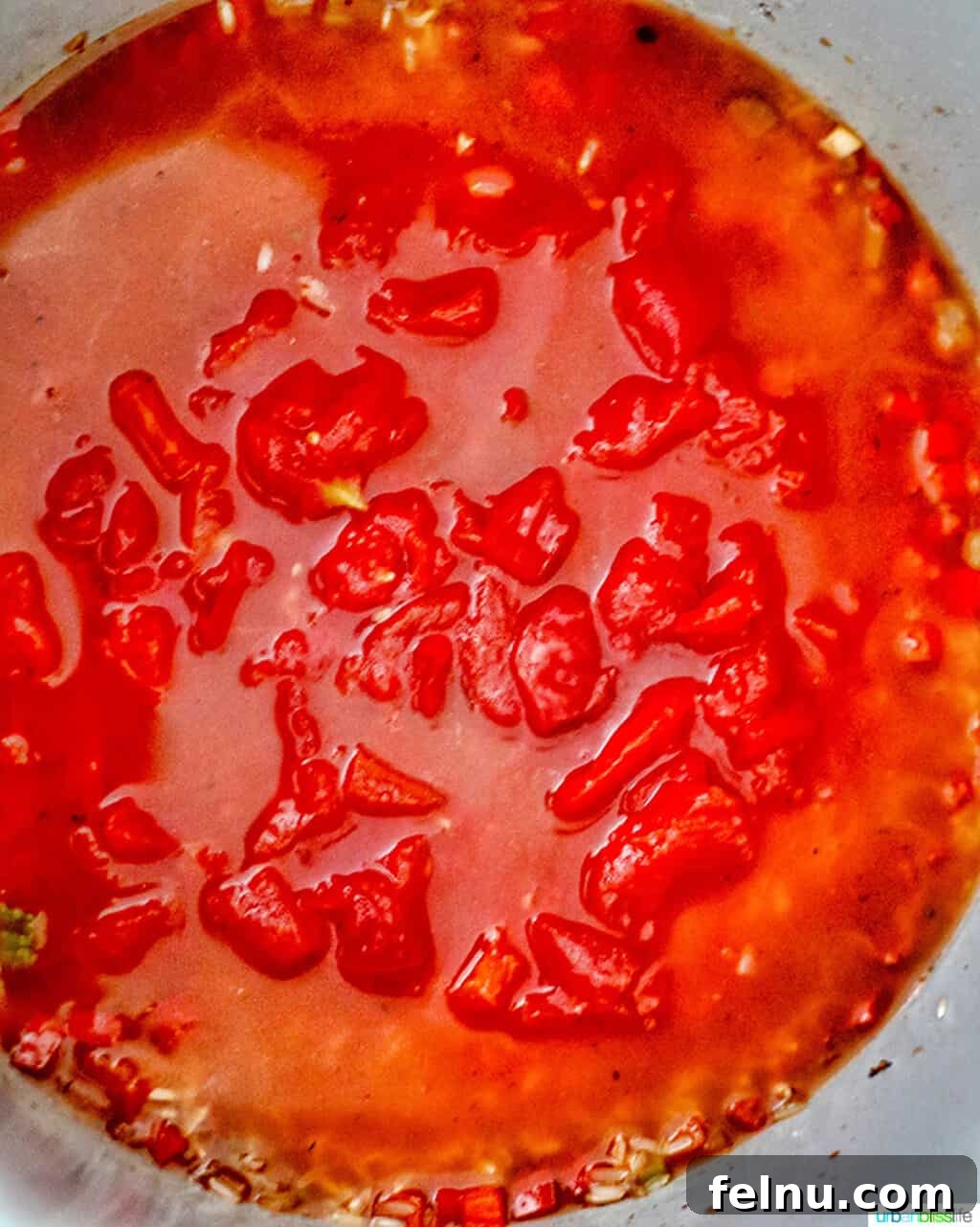 Seafood Jambalaya: A Ninja Foodi Delight 5 Diced tomatoes and rice being added to the Ninja Foodi, building the layers of flavor in the seafood jambalaya.