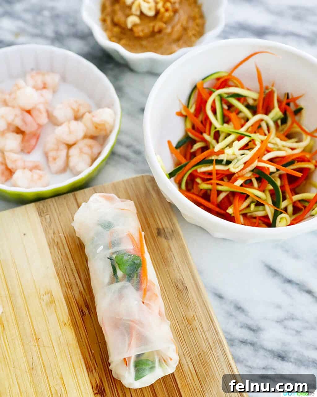A finished shrimp summer roll with ingredients in bowls, ready to be enjoyed.