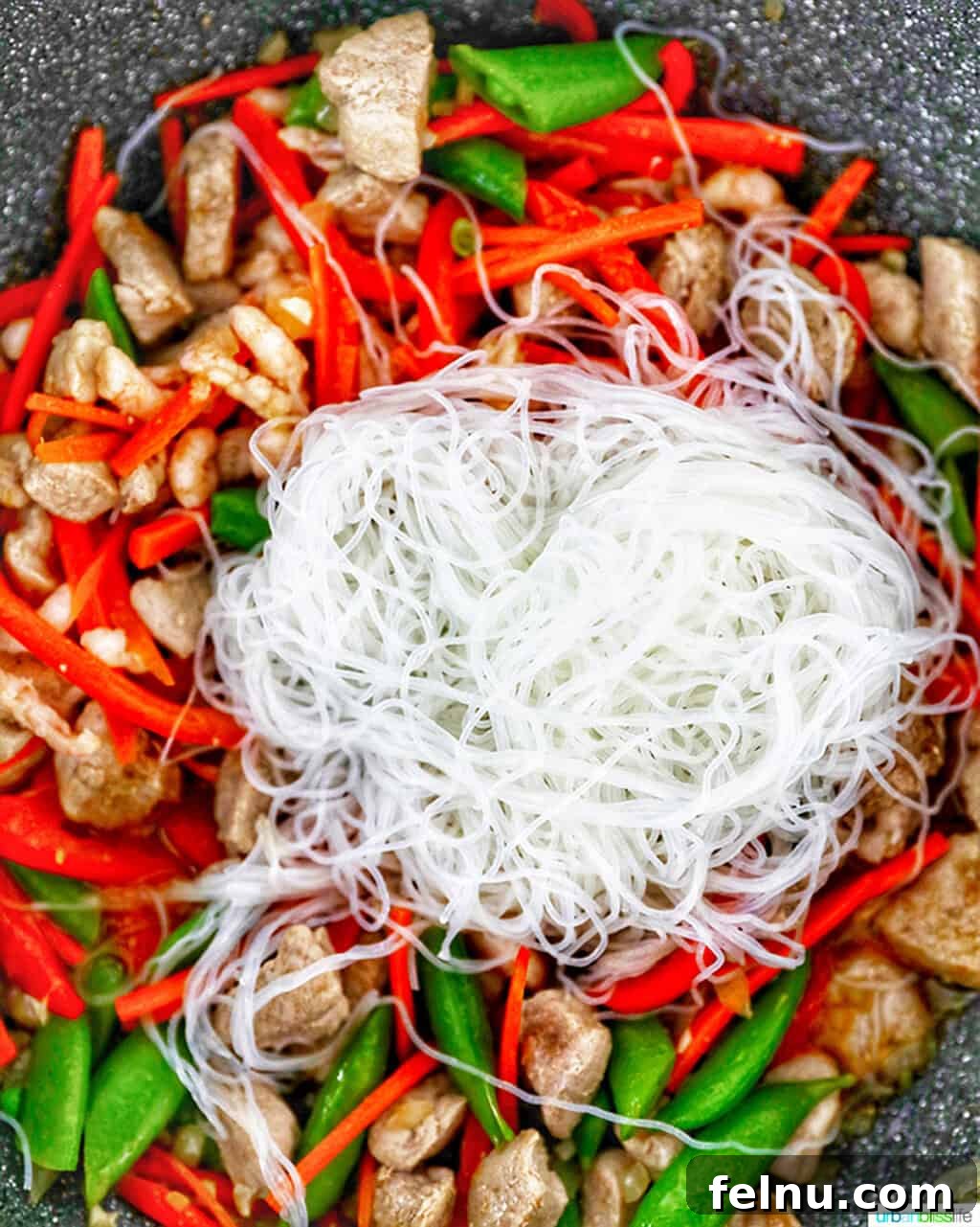 Filipino Pancit Bihon Delight 11 Adding the soaked noodles to the wok for Filipino Pancit Bihon.