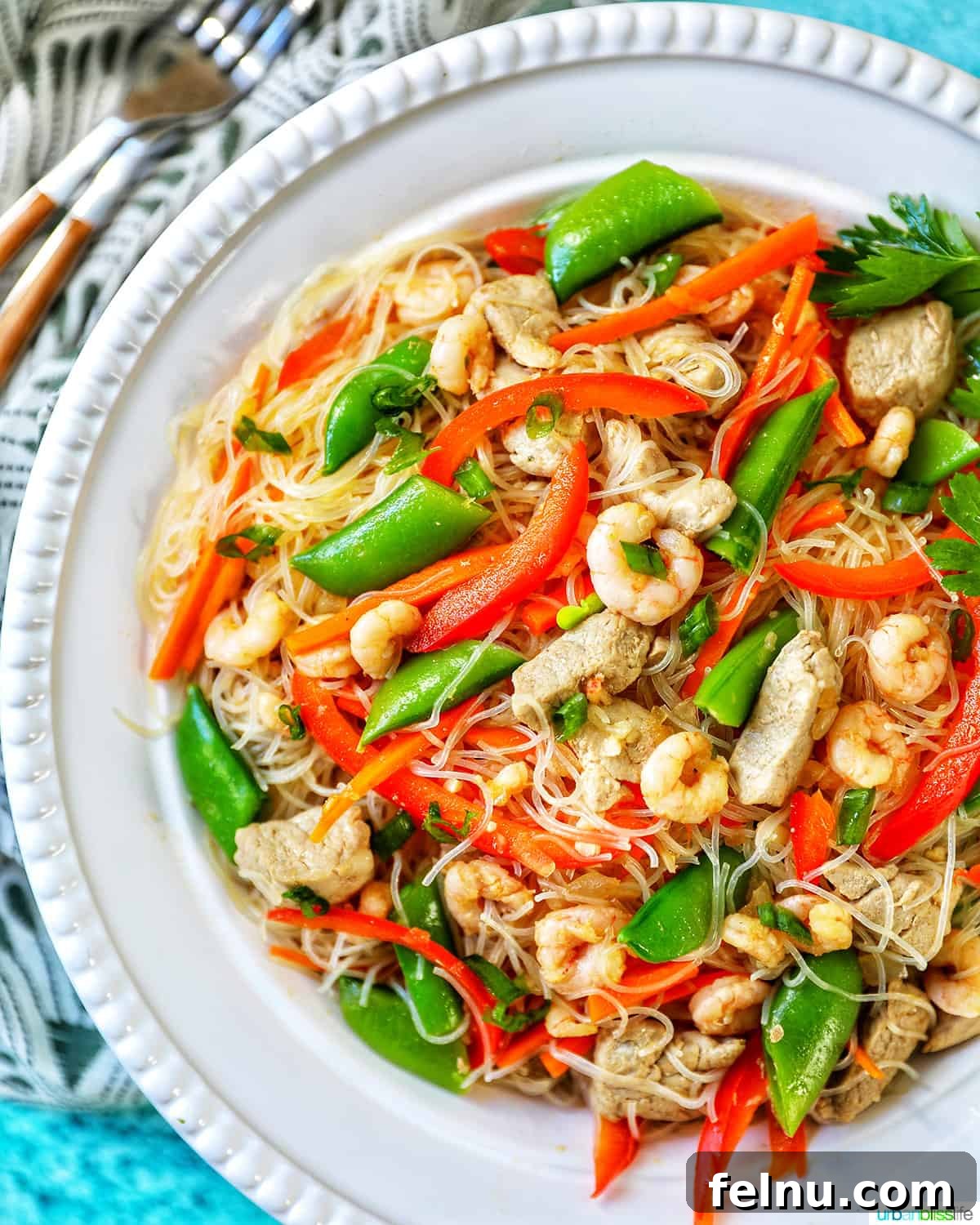 Filipino Pancit Bihon Delight 3 Side view of Filipino Pancit Bihon - noodles, shrimp, chicken, snap peas, red peppers - in a bowl.