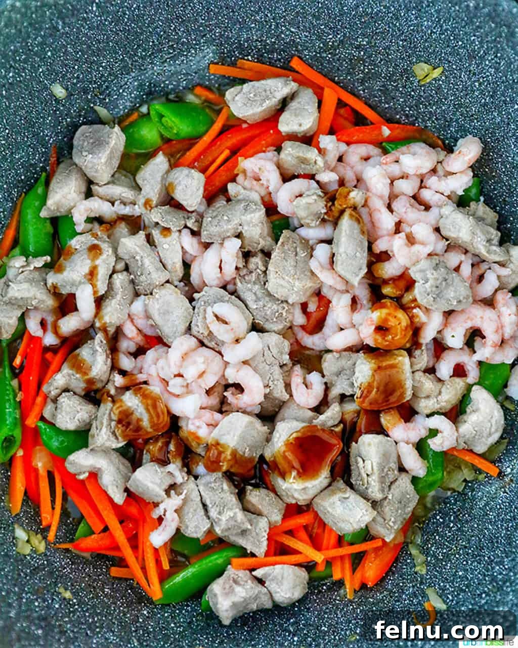 Filipino Pancit Bihon Delight 10 Adding shrimp and pork to the wok with vegetables for Filipino Pancit Bihon.