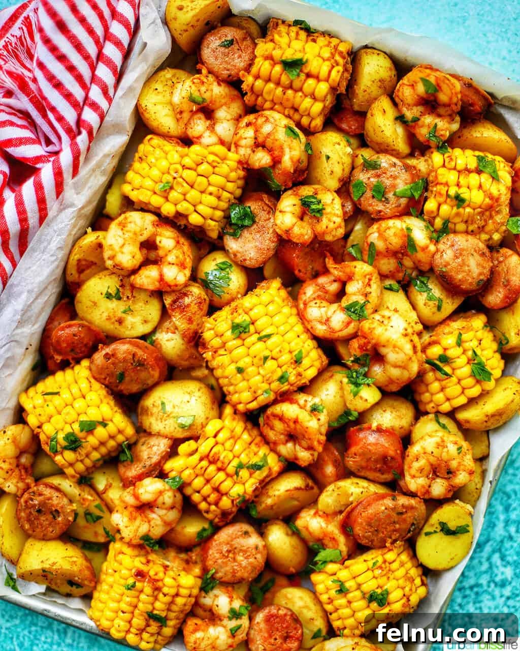 Folyoda Karışık Deniz Mahsulleri 2 tray of seafood, corn, sausage low country boil with blue background and red and white towel