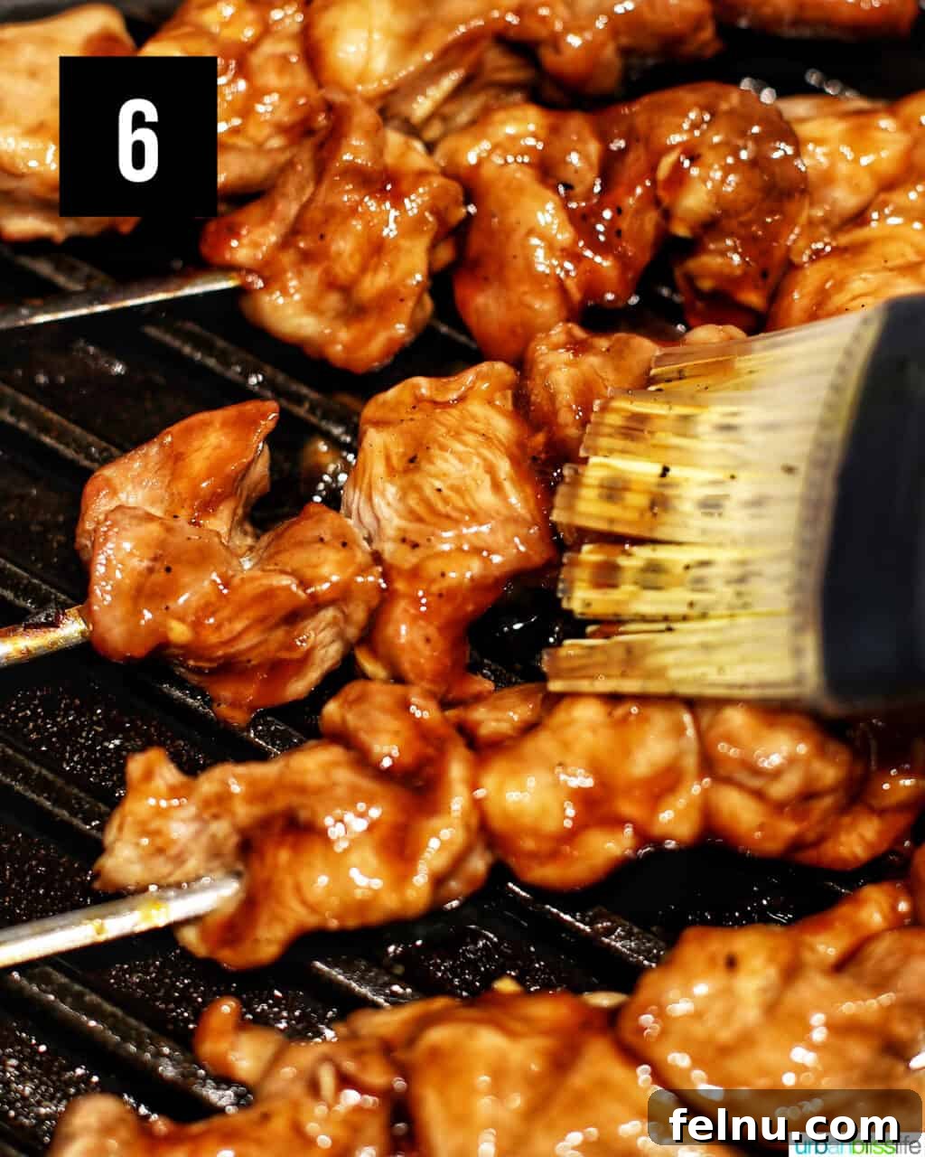 Basting Filipino BBQ pork skewers on the grill