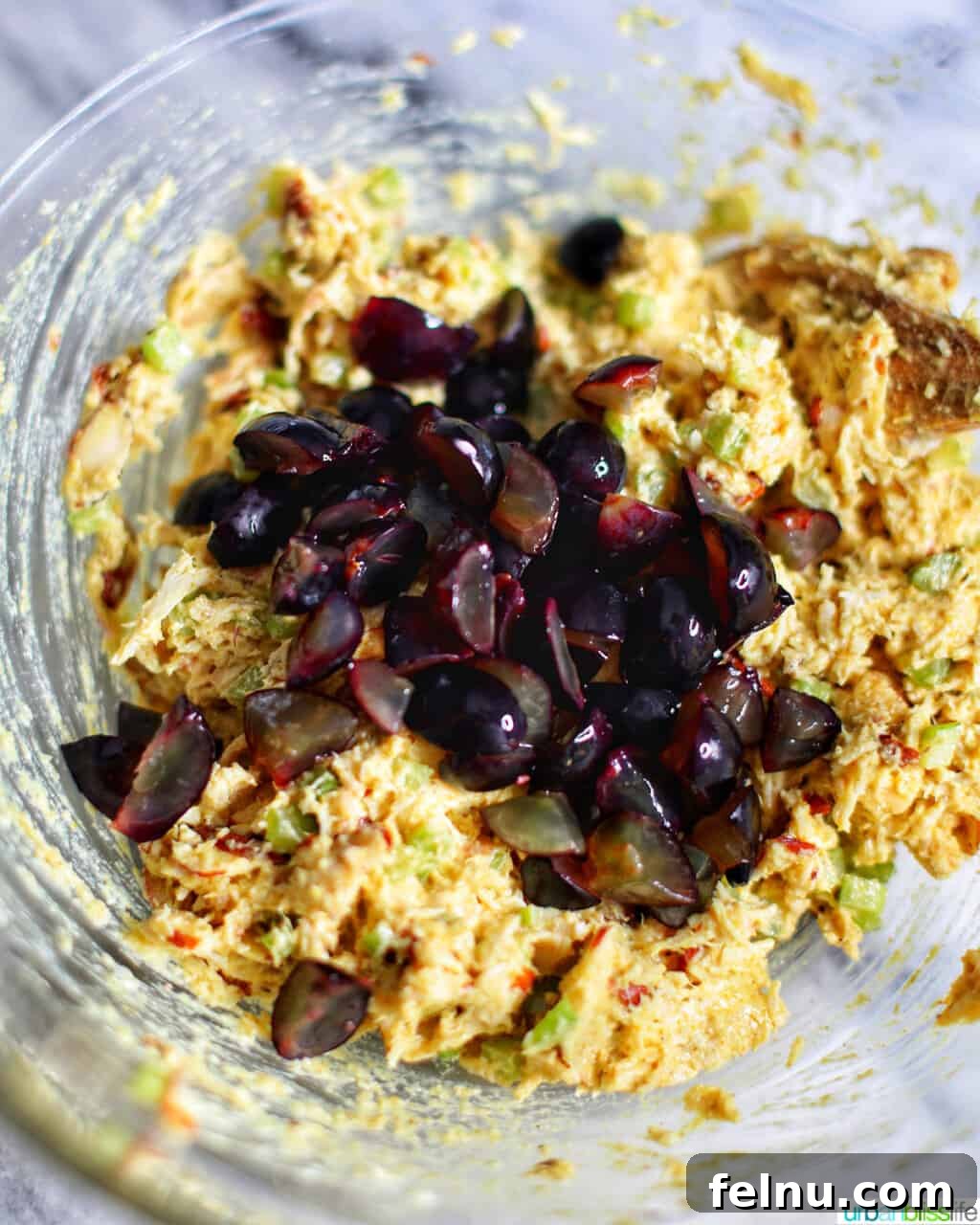 Golden Curry Chicken Salad with Grapes 5 Freshly cut green grapes being added to a large bowl of curry chicken salad mixture, ready for tossing.