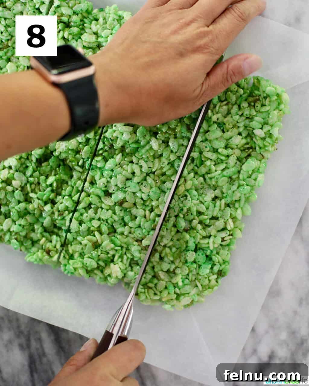 Frankenstein's Monster Munch 12 A large knife slicing the cooled green Rice Krispies treats into even squares in a baking pan.