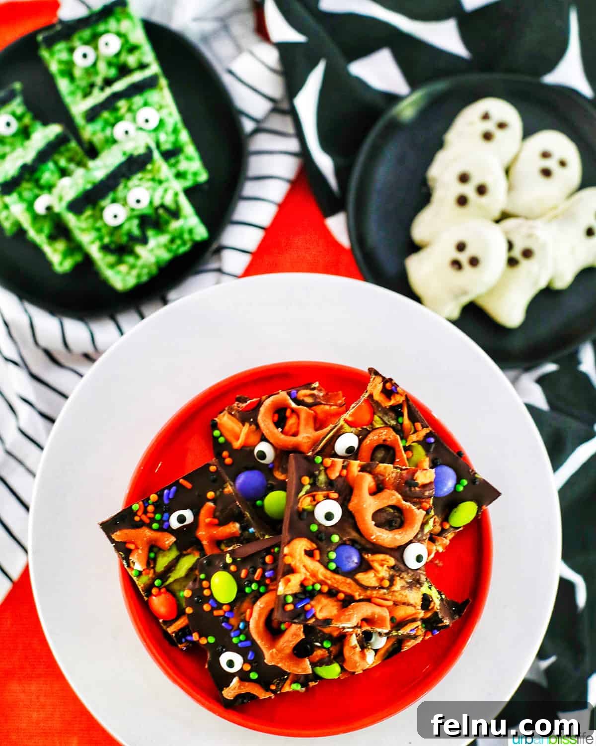 Frankenstein's Monster Munch 16 A vibrant trio of Halloween treats, including Frankenstein Rice Krispies, on orange, black, and white plates, with Halloween bark featured prominently.
