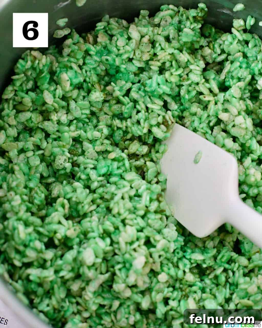 Frankenstein's Monster Munch 10 Mixing the Rice Krispies cereal with the green marshmallow mixture in a large pot, coating the cereal evenly.