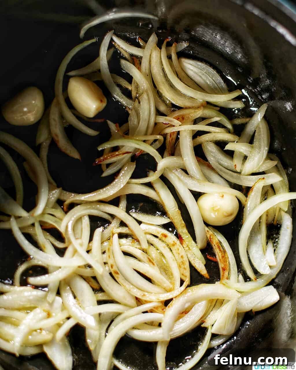 Sliced onions softening in olive oil in a large pot, beginning to turn translucent.