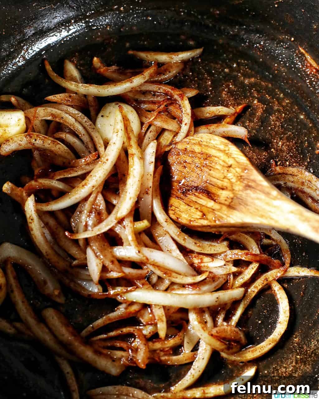 Onions and garlic sautéing with a blend of nutmeg, paprika, and cinnamon in a pot, releasing their aromatic flavors.