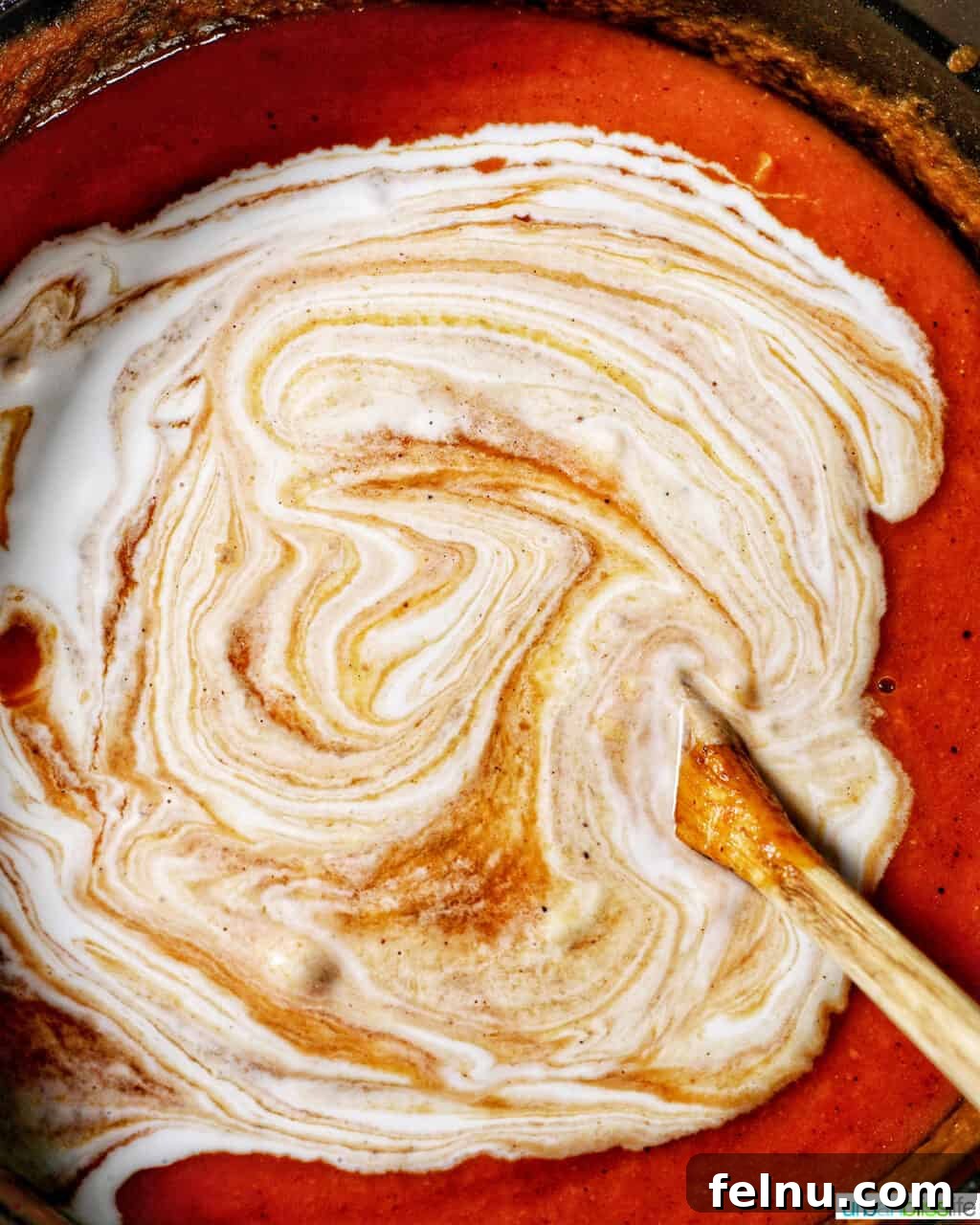 Pumpkin puree, vegetable broth, and coconut cream combined in a pot, being stirred gently to create a smooth, creamy vegan pumpkin soup.