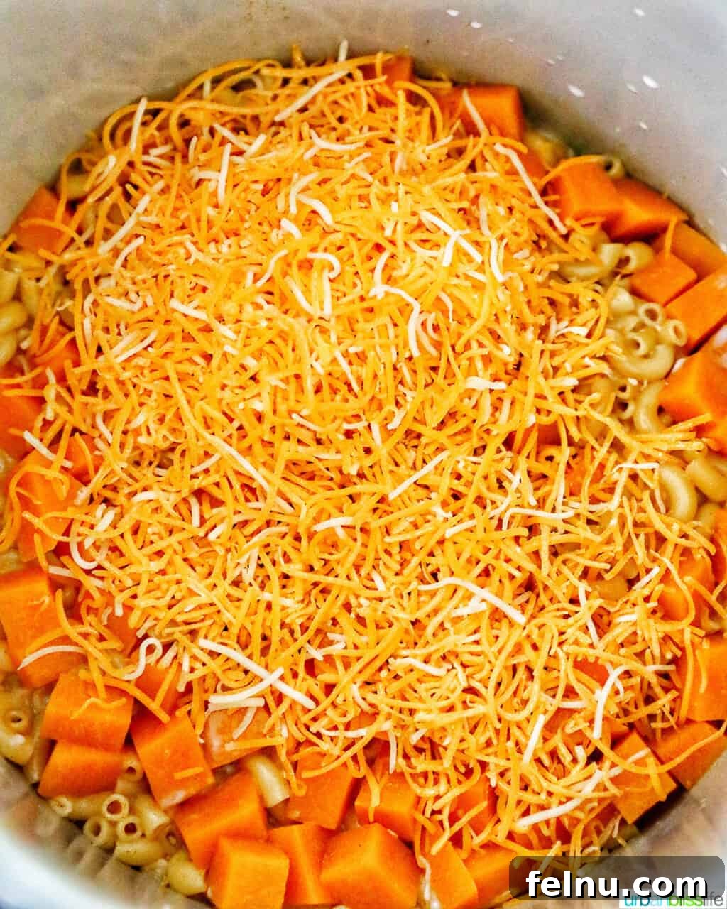 Savory Butternut Instant Pot Mac and Cheese 14 Adding shredded cheddar cheese into the hot pressure cooked macaroni and butternut squash mixture.