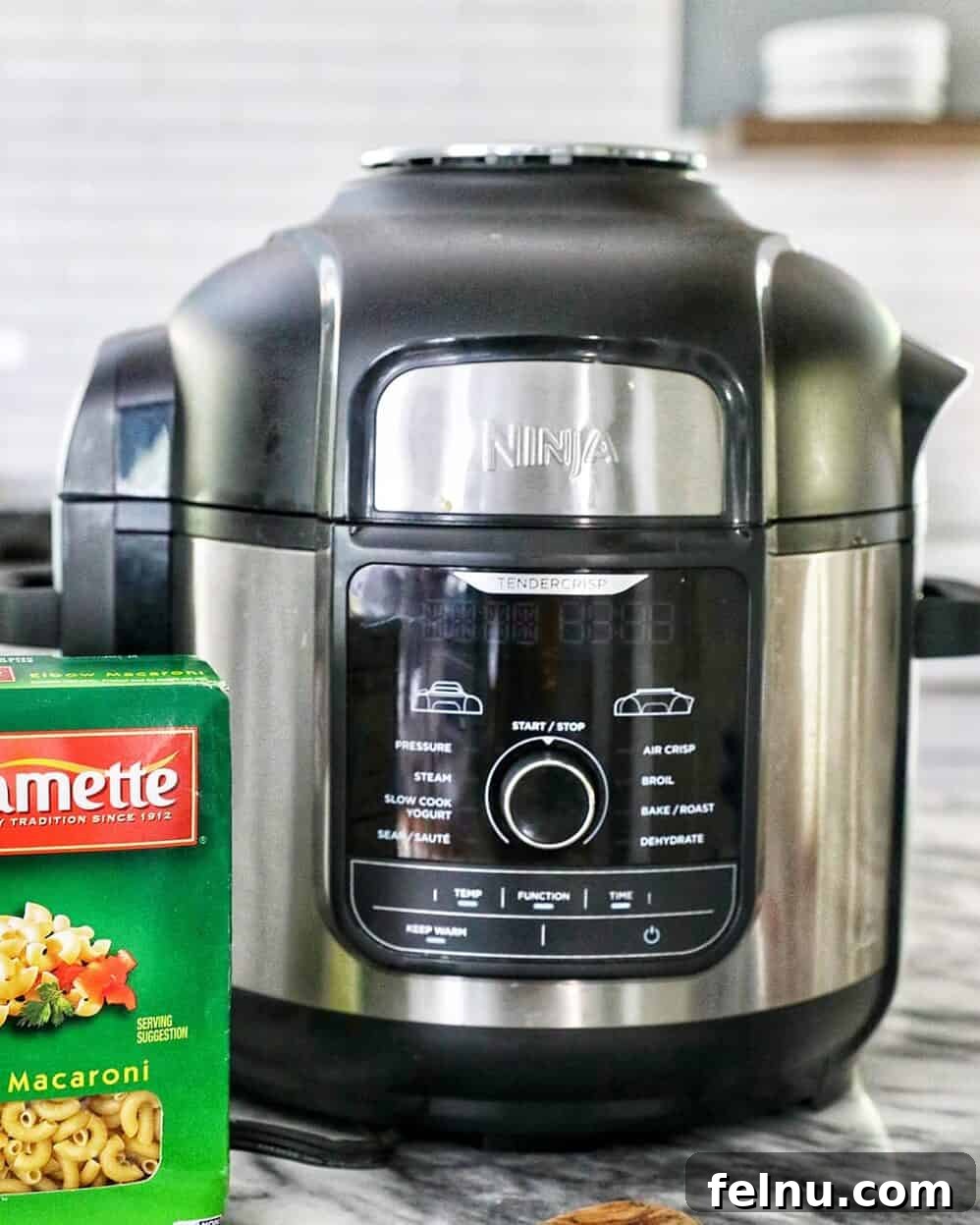 Savory Butternut Instant Pot Mac and Cheese 19 A Ninja Foodi pressure cooker/air fryer beside a box of Creamette Pasta, highlighting key equipment for the recipe.